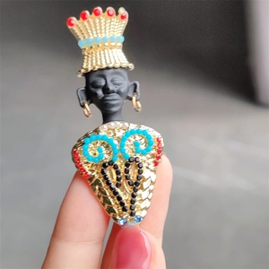 Detail of tribal chief brooch with matte black face, gold crown and colorful rhinestones