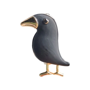 Creative black crow brooch with gold accents and crystal eye on white background