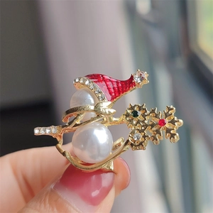Close-up of Christmas snowman brooch with pearls, red enamel hat and colorful rhinestones