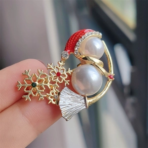 Close-up of a golden Christmas snowman brooch with pearls, red hat, and colorful rhinestones