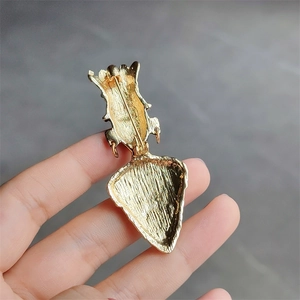 Close-up of the vintage golden tribal brooch back featuring a secure pin and brushed texture