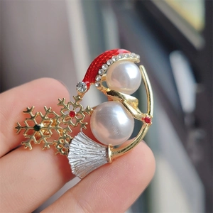 Close-up of Christmas snowman brooch with white pearls, red hat, and crystal details