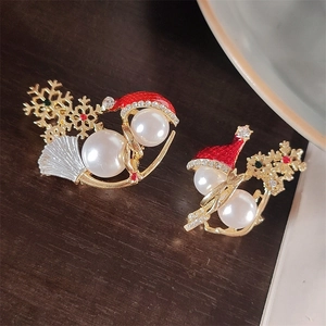 Detailed close-up of a Christmas snowman pin with pearls and rhinestones on a wooden surface
