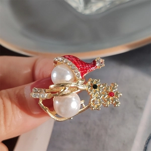 Macro shot of cute Christmas snowman brooch with pearls, red enamel hat and rhinestones