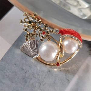 Macro view of Christmas brooch with golden snowflakes, pearls and red enamel hat detail