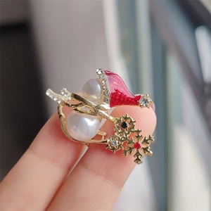 Detailed view of a Christmas snowman brooch with white pearls and red enamel hat
