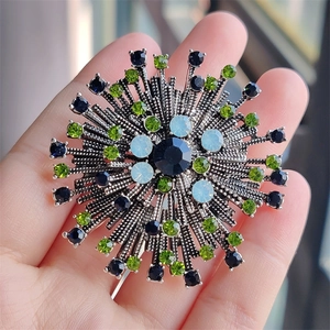 Macro detail of retro floral brooch featuring multicolored crystals and antique metal base