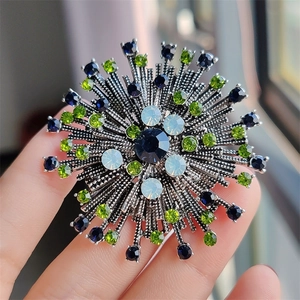 Detail of vintage flower brooch with blue and green rhinestones on silver base