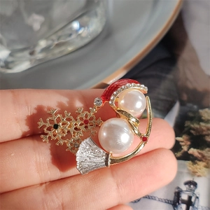 Macro detail of Christmas snowman brooch with pearls, red enamel hat and gold snowflake