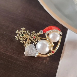 Macro detail of Christmas snowman brooch with pearls, red hat and snowflake elements