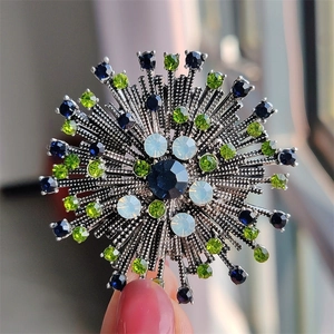 Close-up of vintage sunflower brooch with blue and green crystals on silver base