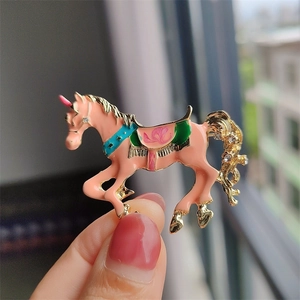 Dettaglio della spilla a forma di unicorno in smalto rosa con bordi dorati e strass