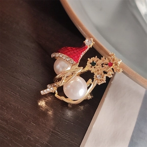 Close-up of pearl snowman brooch with red Christmas hat and colorful rhinestones