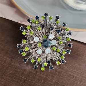 Close-up of vintage flower brooch with blue rhinestones and silver sunburst pattern texture