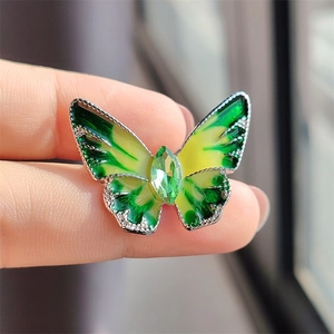 Detailopname van een groene vlinderbroche met kristallen edelsteen en een zilverkleurige rand