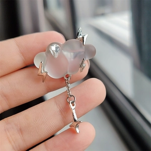 Detailed shot of creative cloud brooch with metal lightning and a silver star pendant