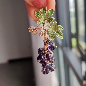 Detailed view of grape brooch with purple crystals and green leaves on gold plating