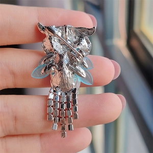 Macro view showing the silver alloy pin back mechanism and hanging fringe chains on the brooch
