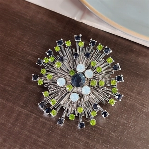Macro detail of silver starburst brooch with dark blue and green faux gemstones