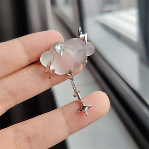 Detail of matte white cloud brooch with silver lightning bolts and star pendant charm