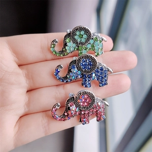 Detailed view of three small elephant brooches with colorful rhinestones held by a hand