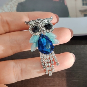 Detail of owl brooch featuring blue teardrop crystal and sparkling diamond tassels
