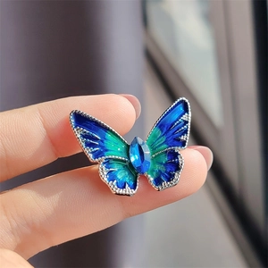 Detail van vlinderbroche met blauw emaille verloop en marquise edelsteen in het midden