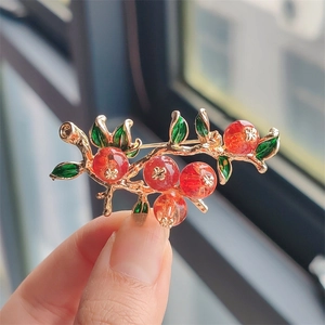 Elegant botanical persimmon brooch featuring red crystal berries and green enamel leaves