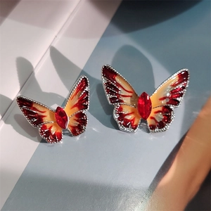 Macro-opname van vlinder oorbellen met rood emaille en centraal rode edelsteen detail