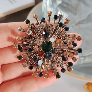 Detailed view of vintage sunburst brooch with colorful rhinestones held by hand