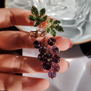 Macro shot of sweet grape cluster brooch with purple beads and green enamel leaves