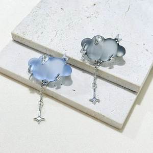 Detail of cloud-shaped earrings with matte finish, silver lightning, and star pendants