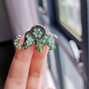 Close-up of elephant brooch with green and blue rhinestones on silver metal base