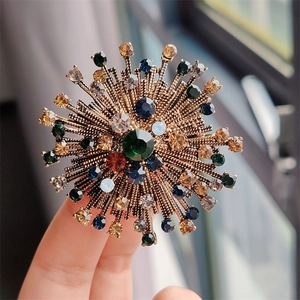 Close-up of vintage gold starburst brooch with colorful rhinestones held by hand