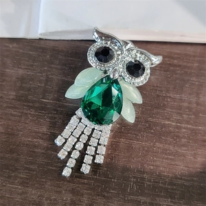 Detail of owl brooch with emerald teardrop crystal and sparkling rhinestone tassels