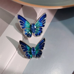 Detail van blauwe emaille vlinderbroches met kristalinleg in twee maten voor jassen