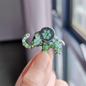 Macro detail of elephant brooch with inlaid green crystals and floral ear design