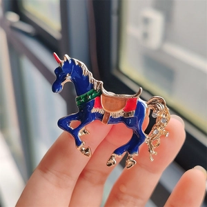 Dettaglio di una spilla a forma di unicorno in smalto blu con placcatura in oro e strass