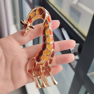 Detail view of artistic giraffe brooch with golden alloy and colorful enamel texture