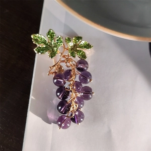 Macro detail of the elegant grape cluster brooch with purple beads and green zircon leaves