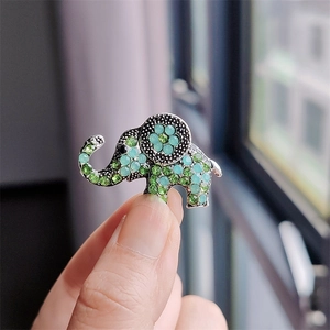Macro detail of elephant brooch with sparkling green and mint rhinestones held in hand
