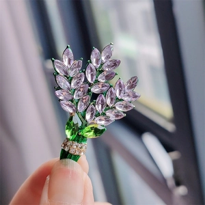 Macro detail of a purple crystal lavender brooch with elegant green leaf accents