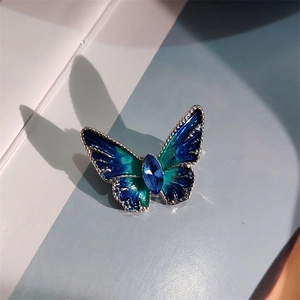 Macro detail van vlinderbroche met blauw en groen verloop emaille en kristallen midden