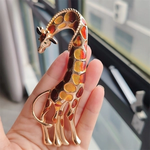 Macro detail of giraffe brooch featuring amber enamel inlay and green crystal eye detail