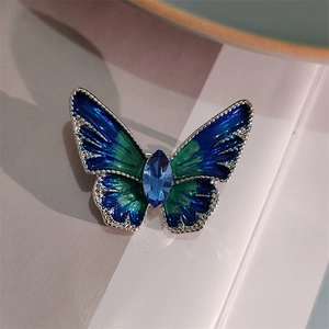 Macro-opname van de blauw-groene vlinderbroche met een gefacetteerde kristallen steen