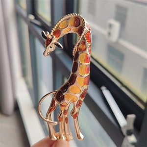 Close-up of giraffe brooch with colorful enamel spots and green gemstone eye detail