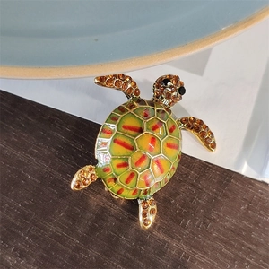 Macro detail of turtle brooch with vibrant green enamel shell and amber rhinestones