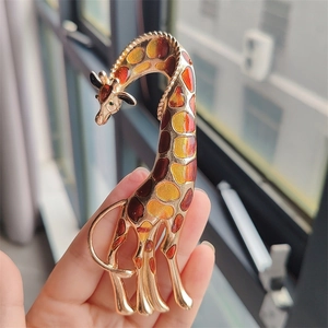 Detailed view of handmade enamel giraffe brooch with golden plating and vivid colors
