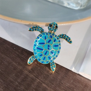 Macro detail of turtle brooch with blue rhinestones and enamel on a golden base