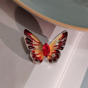 Macro-opname van vlinderbroche met rood geel emaille en ingelegde rode kristallen